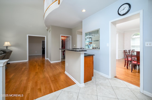 kitchen featuring baseboards, open floor plan, light wood-style flooring, and dark countertops