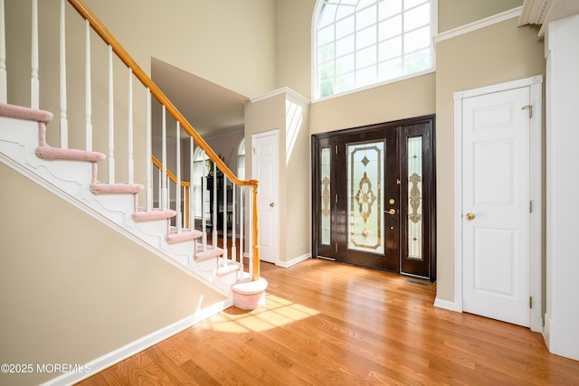 entrance foyer with stairs, a high ceiling, baseboards, and wood finished floors