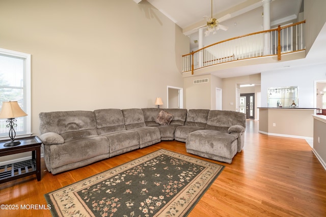 living area with a ceiling fan, a high ceiling, visible vents, and wood finished floors