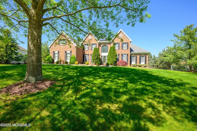 traditional-style house featuring a front lawn and brick siding
