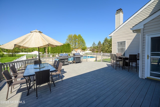 wooden deck with a fenced in pool, outdoor dining area, and a grill