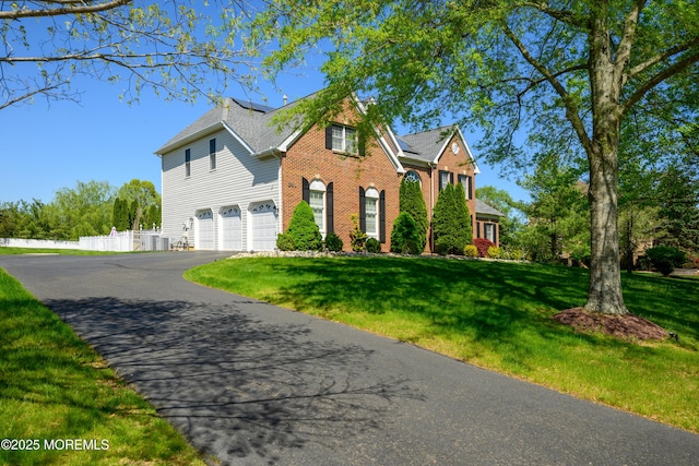 traditional home with a garage, fence, a front yard, and aphalt driveway