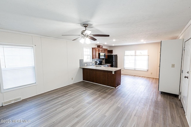 89 Woodchuck Pkwy, Whiting, NJ 08759 - kitchen with freestanding refrigerator, a peninsula, stainless steel microwave, a ceiling fan, and visible vents