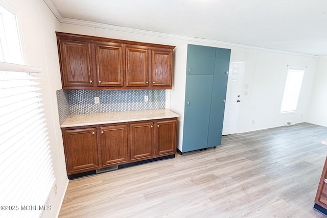 89 Woodchuck Pkwy, Whiting, NJ 08759 - kitchen with crown molding, brown cabinets, light wood-style floors, light countertops, and backsplash