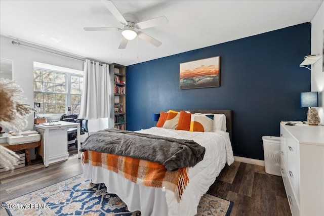 bedroom featuring an accent wall, a ceiling fan, and wood finished floors