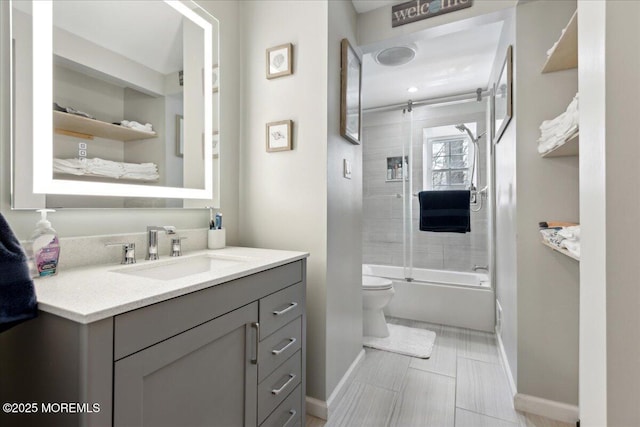 full bathroom with baseboards, shower / bath combination with glass door, toilet, and vanity