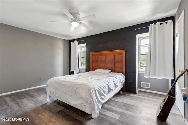 bedroom with baseboards, multiple windows, wood finished floors, and visible vents