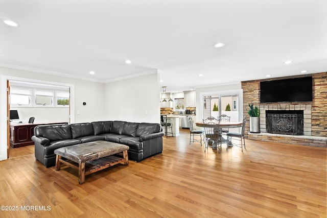 living area with recessed lighting, ornamental molding, light wood-style flooring, and a fireplace