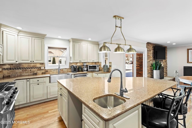 kitchen featuring light stone counters, high end stainless steel range, a sink, and light wood-style floors
