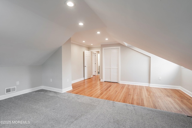 additional living space featuring visible vents, wood finished floors, baseboards, recessed lighting, and vaulted ceiling