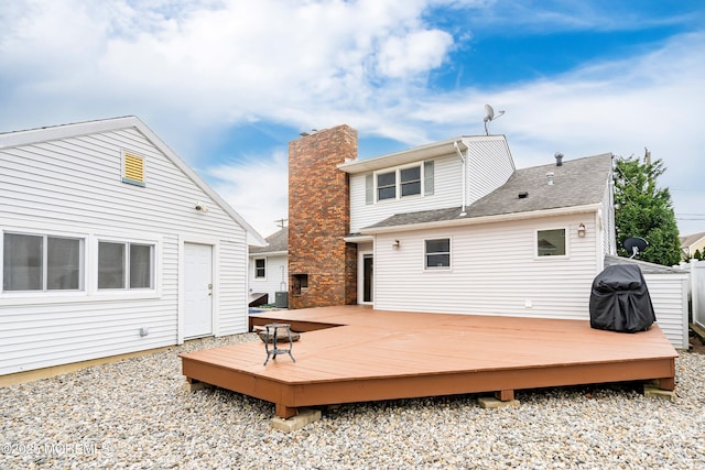 exterior space with a wooden deck, a shingled roof, and a chimney