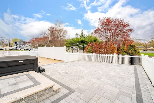 view of patio featuring fence and a hot tub