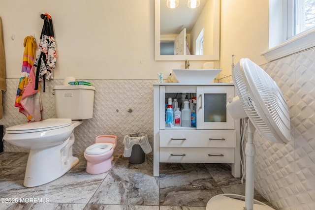 1603 Berkeley Ave, Beachwood, NJ 08722 - bathroom featuring toilet, tile walls, a sink, marble look tile flooring, and a wainscoted wall