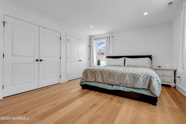 bedroom with crown molding, two closets, light wood-style flooring, recessed lighting, and baseboards