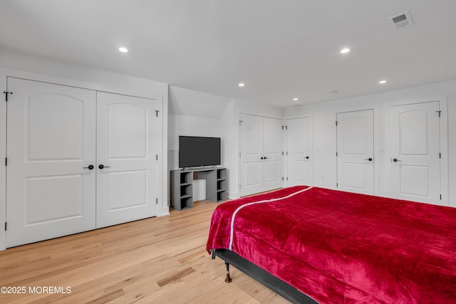 bedroom featuring multiple closets, light wood-style flooring, and recessed lighting