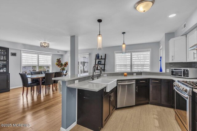 kitchen with visible vents, pendant lighting, appliances with stainless steel finishes, a sink, and a peninsula