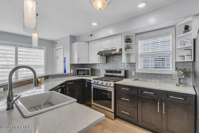 kitchen featuring open shelves, a sink, white cabinets, under cabinet range hood, and stainless steel appliances