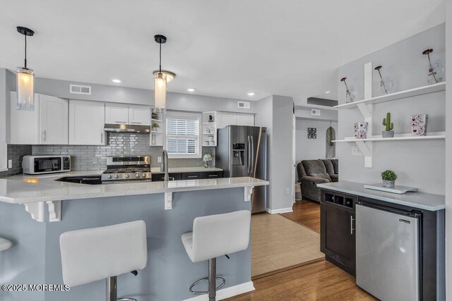 kitchen with visible vents, appliances with stainless steel finishes, open shelves, a peninsula, and under cabinet range hood