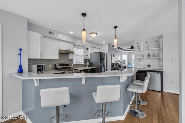 kitchen featuring visible vents, open shelves, light countertops, under cabinet range hood, and stainless steel appliances