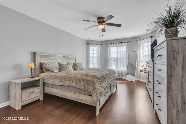 bedroom featuring a ceiling fan, baseboards, multiple windows, and dark wood-type flooring