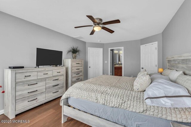 bedroom featuring connected bathroom, dark wood-style flooring, and ceiling fan