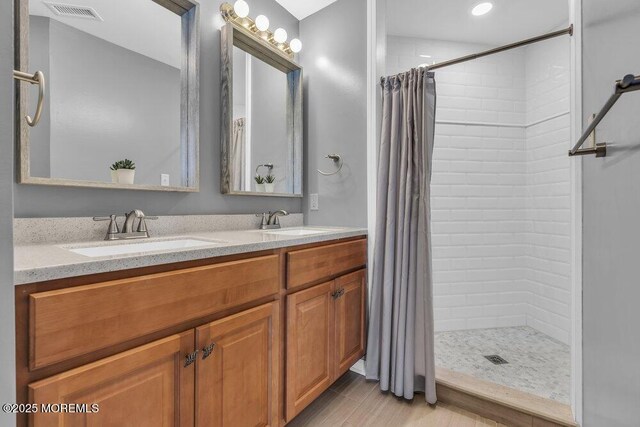 bathroom featuring visible vents, a tile shower, and a sink