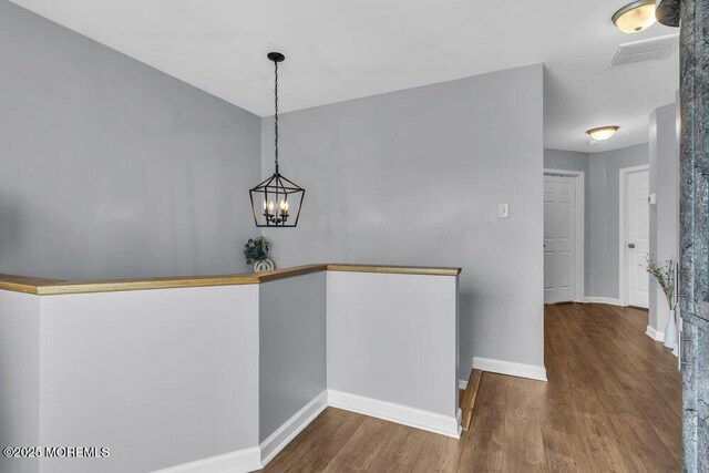 interior space featuring visible vents, baseboards, wood finished floors, and an inviting chandelier