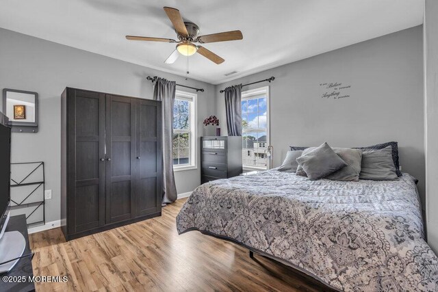 bedroom with baseboards, a ceiling fan, light wood-style flooring, and visible vents