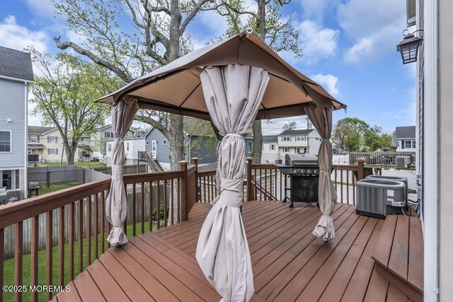 deck with area for grilling, a residential view, central air condition unit, a gazebo, and fence