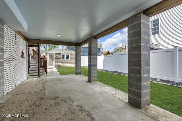 view of patio / terrace with a fenced backyard, an outbuilding, and stairs