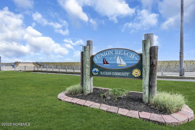 community / neighborhood sign featuring a lawn, fence, and a rural view