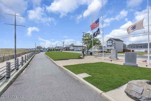 view of property's community featuring a lawn and fence