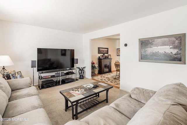 carpeted living area featuring baseboards and a glass covered fireplace