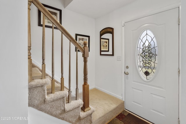 foyer entrance featuring stairway, carpet floors, and baseboards