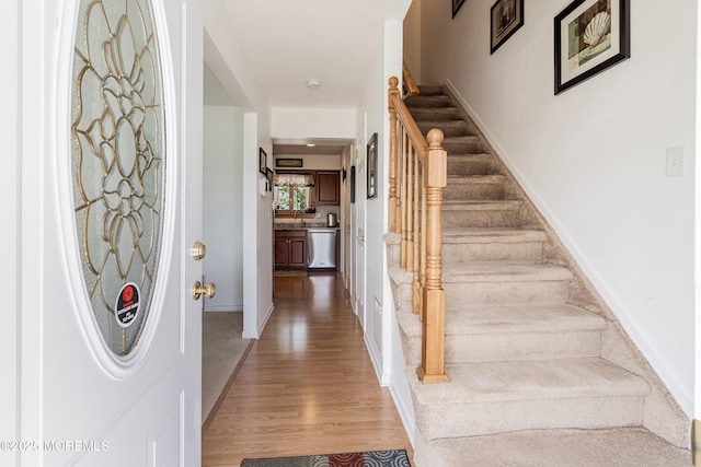 entrance foyer featuring baseboards, light wood-style floors, and stairway