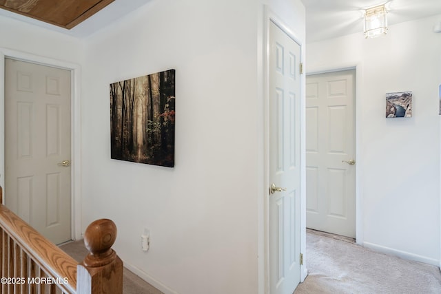 hall featuring light carpet and baseboards