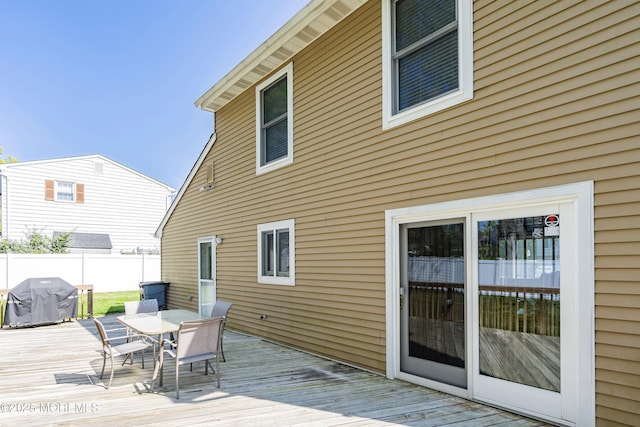 wooden deck featuring a grill, outdoor dining space, and fence