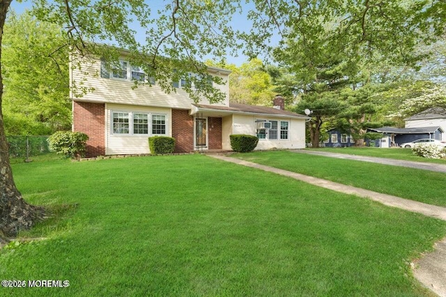 colonial house with brick siding, fence, and a front lawn