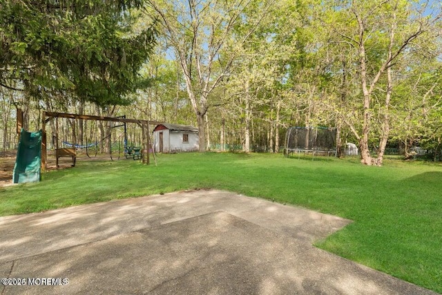 view of yard with a playground, a trampoline, an outbuilding, and a patio