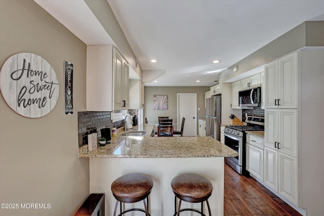 kitchen featuring a kitchen breakfast bar, appliances with stainless steel finishes, tasteful backsplash, and a peninsula