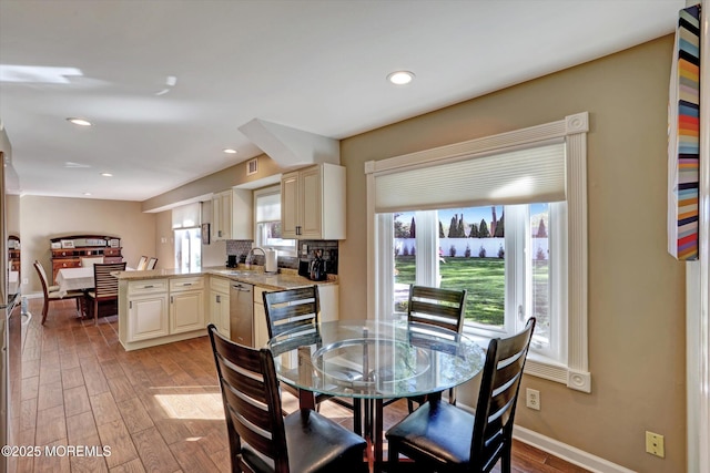 dining area featuring visible vents, light wood-style flooring, a water view, and a healthy amount of sunlight