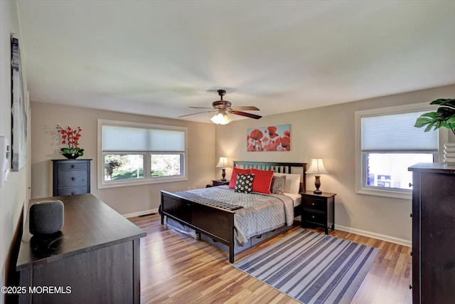 bedroom featuring baseboards, multiple windows, and wood finished floors