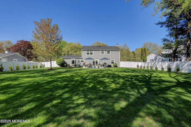 rear view of house with a yard, a patio, a chimney, and a fenced backyard