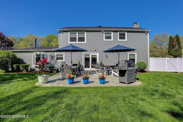 back of property featuring fence, a patio, a chimney, and a lawn