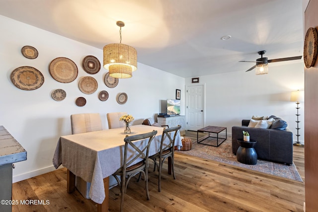 dining space featuring baseboards, a ceiling fan, and wood finished floors
