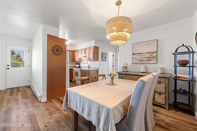 dining area with an inviting chandelier, baseboards, a baseboard heating unit, and light wood-style flooring