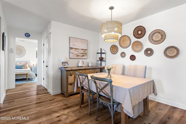 dining area with baseboards, a chandelier, and light wood-style flooring