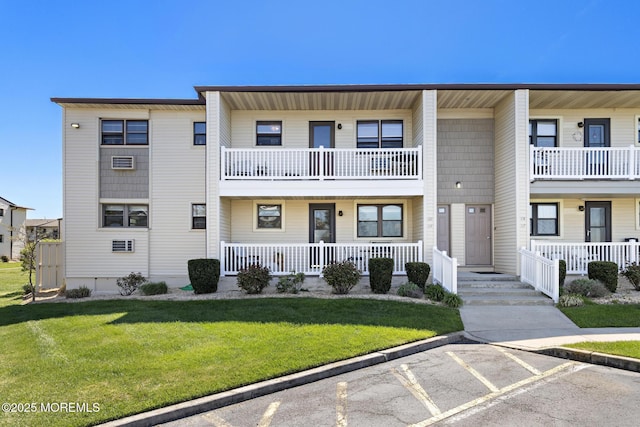 townhome / multi-family property featuring a front lawn, a porch, uncovered parking, and a balcony