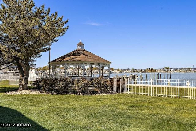 dock area with a lawn, a water view, a gazebo, and fence