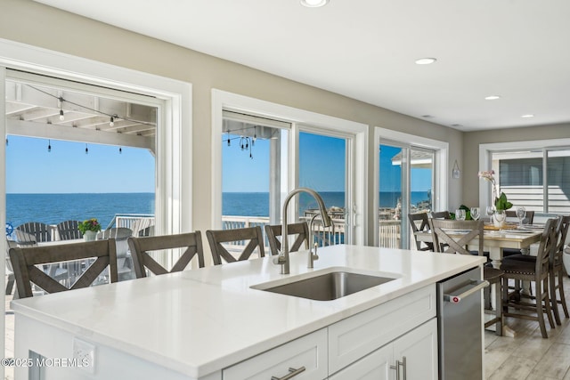 kitchen featuring plenty of natural light, a sink, a water view, and white cabinets